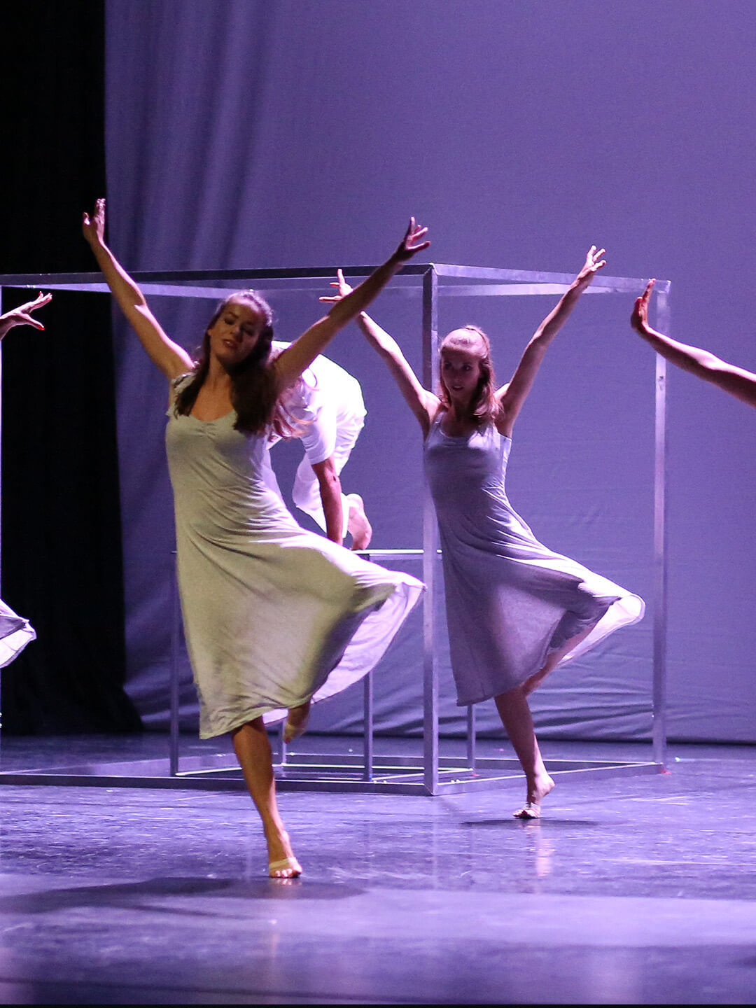 Tanzende Frauen mit gestreckten Armen vor einem lilafarbenen Hintergrund